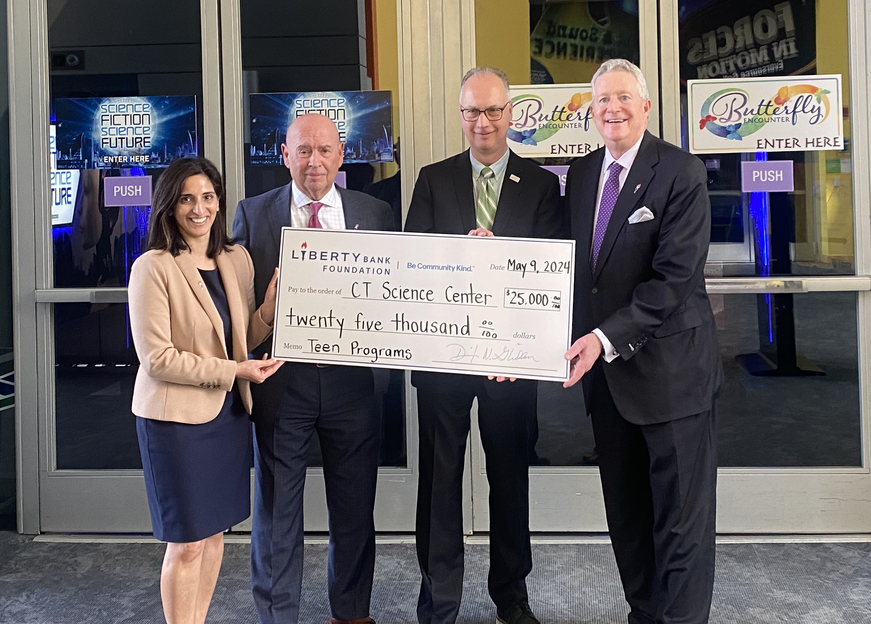 Four people holding a large grant check